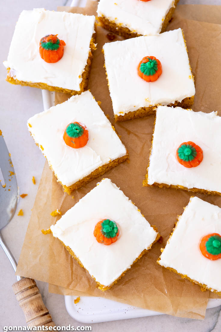 Slices of Pumpkin Bars with Cream Cheese Frosting, decorated with candy pumpkin, top shot