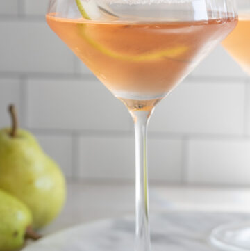 a glass of pear martini, garnished with a slice of pear