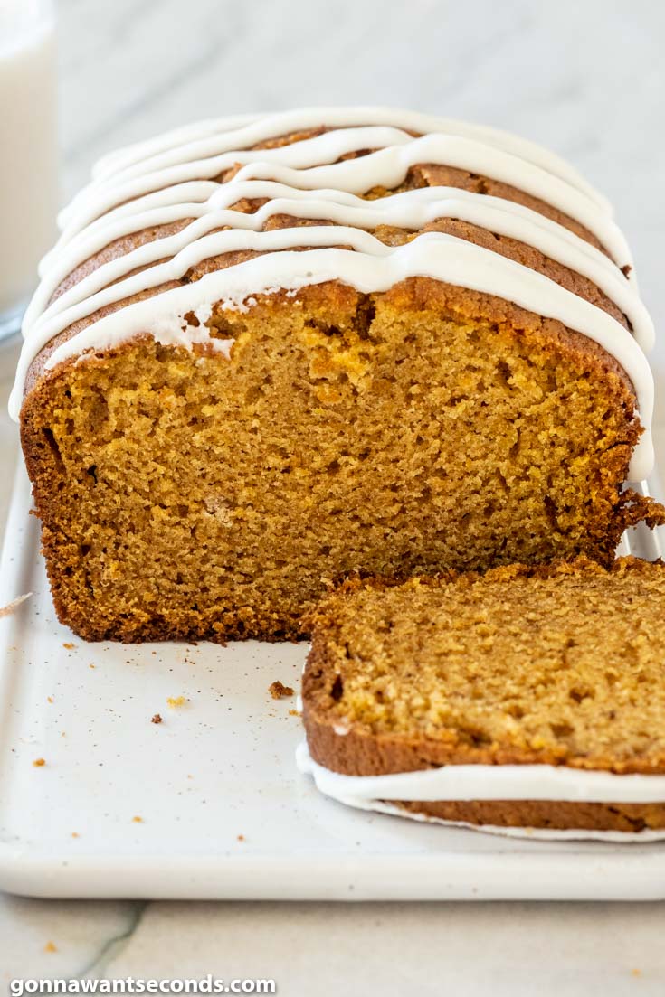 a loaf of easy pumpkin bread with glaze on top, with slice on the side
