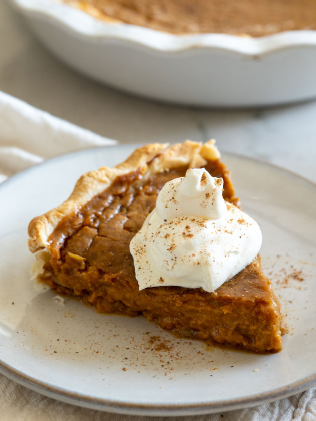 A slice of pumpkin pie topped with a dollop of whipped cream