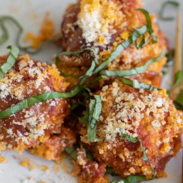 chicken parmesan meatballs on a plate with garnish on top