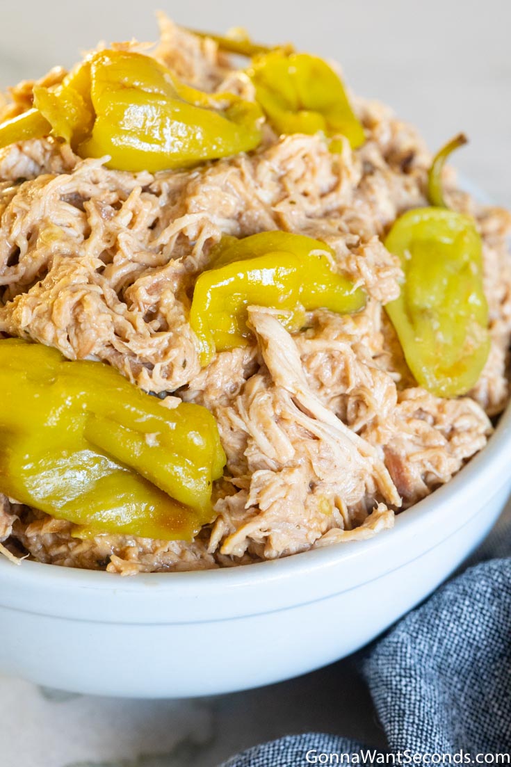 mississippi chicken crock pot, topped with pepperoncini, in a bowl