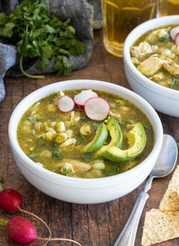 Bowls of pozole verde, topped with sliced avocados and radishes