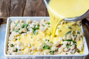 Pouring egg mixture over strata