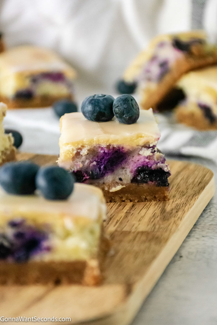 slices of blueberry cheesecake bars topped with fresh blueberries 