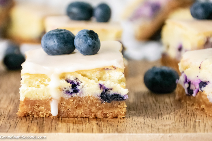 slices of blueberry cheesecake squares topped with fresh blueberries