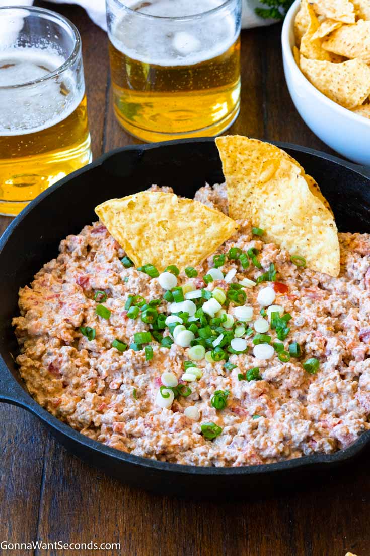 sausage cream cheese rotel dip in a cast-iron skillet with tortilla chip 