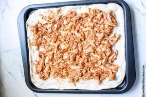 How to make sheet pan BBQ chicken pizza , spreading chicken on the dough