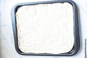 How to make simple sheet pan chicken , spreading pizza dough on sheet pan