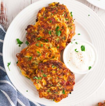 zucchini corn fritters with dipping sauce on the side, on a plate