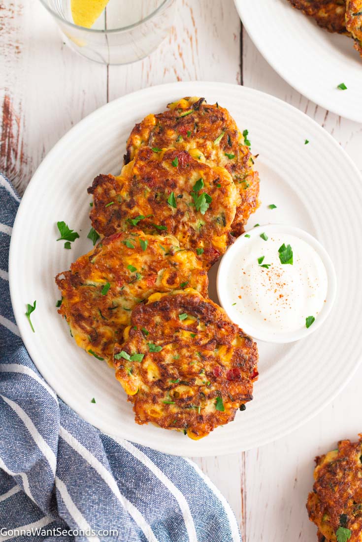 zucchini corn fritters with dipping sauce on the side, on a plate