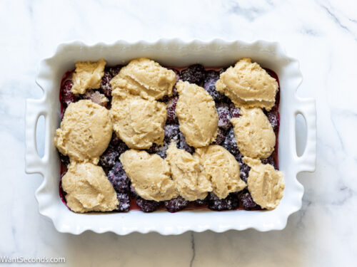 how to make easy blackberry cobbler, add cake topping on top of the fruit filling