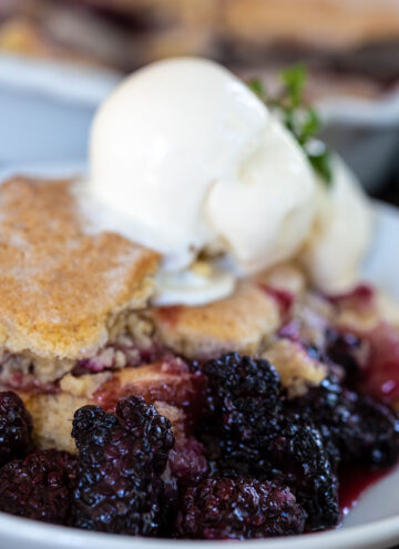 blackberry cobbler with vanilla ice cream on top, on a plate