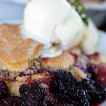 blackberry cobbler with vanilla ice cream on top, on a plate