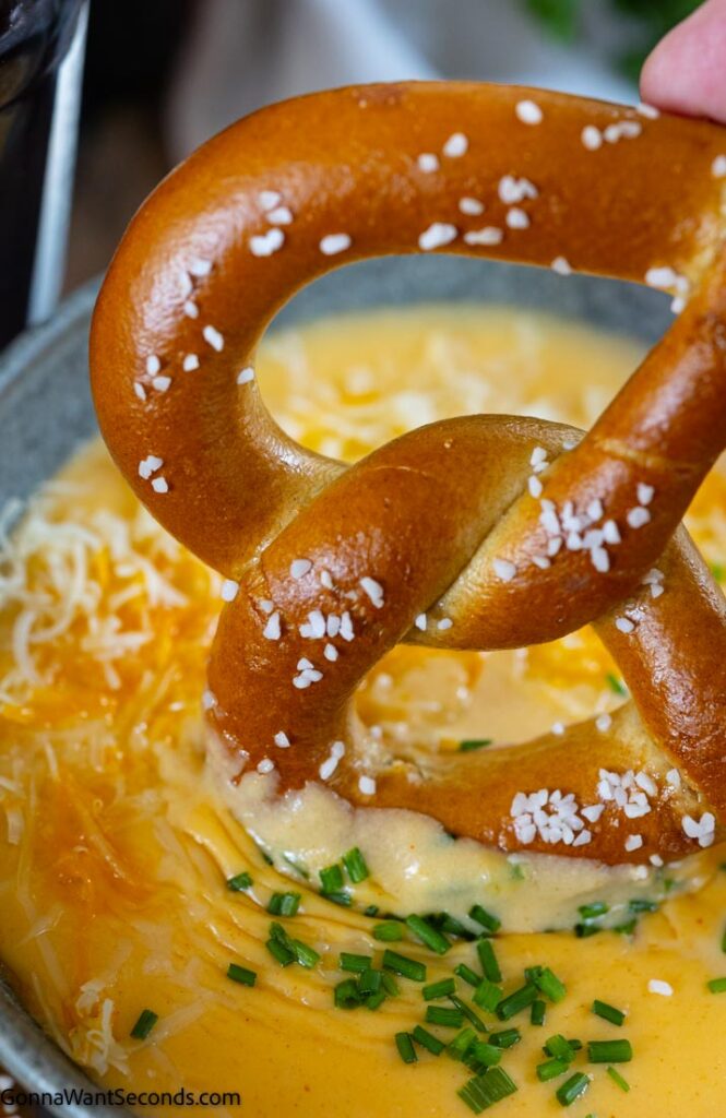 dipping the pretzel in the beer cheese dip gruyere