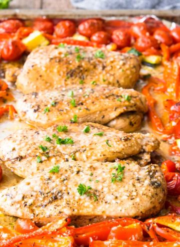 Italian Chicken nestled in mixed vegetables on a sheet pan, close up
