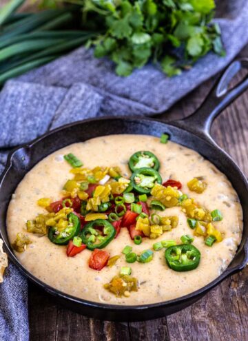 white Queso dip topped with jalapenos dip on a cast iron skillet
