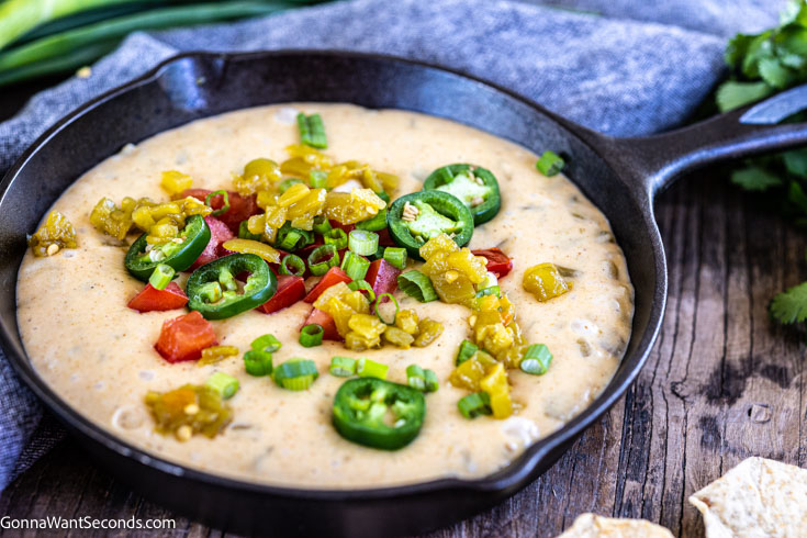 queso cheese dip topped with jalapenos dip on a cast iron skillet