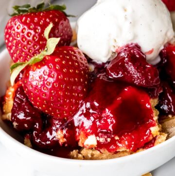strawberry dump cake topped with fresh strawberries and vanilla ice cream