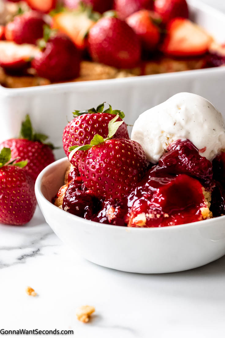 strawberry dump cake with yellow cake mix topped with fresh strawberries and vanilla ice cream