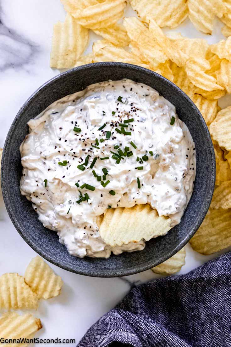 a bowl of sour cream french onion dip with chips around 