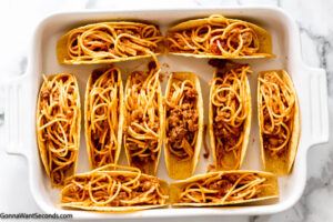 Step 5 how to make spaghetti tacos, add spaghetti mixture into the taco shells