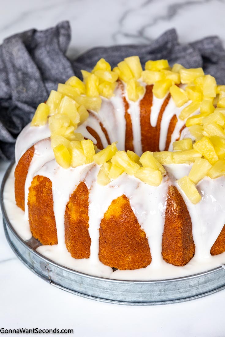 whole moist pineapple pound cake with glaze and pineapple tidbits on top
