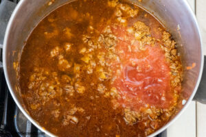 Step 4 how to make ground beef taco mac and cheese, add the beef broth and tomato sauce