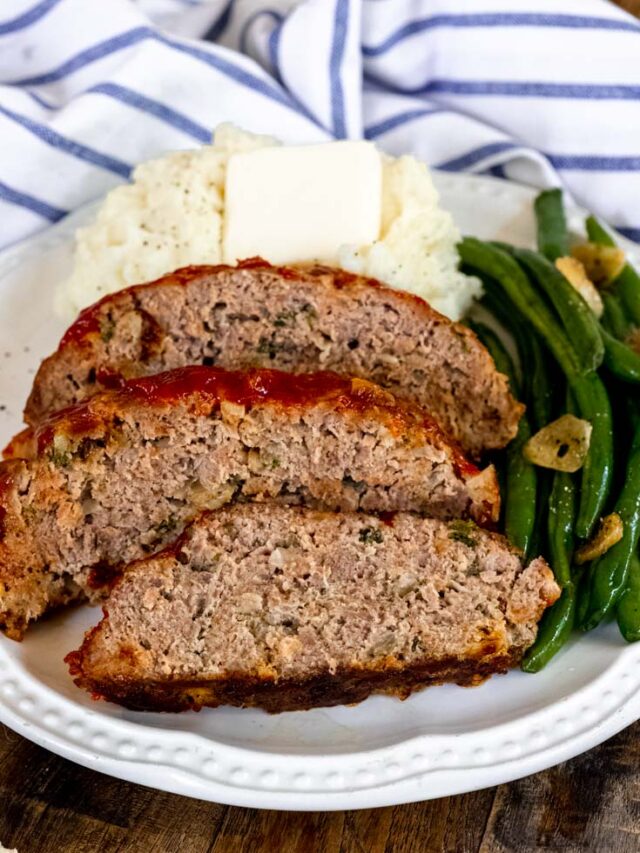 Slices of traditional meatloaf recipe with mashed potato and green beans on a plate