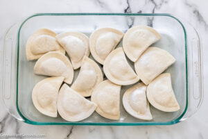 Step 1 how to make pierogi casserole , spread half the frozen pierogies in the casserole dish