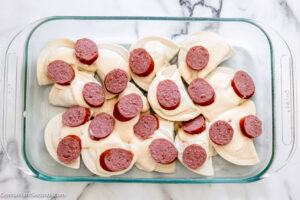 Step 3 how to make pierogi casserole with kielbasa , spread half the kielbasa over the pierogies and sauce