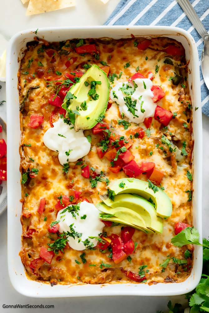 chicken fajita casserole topped with sliced avocados, sour cream and tomatoes