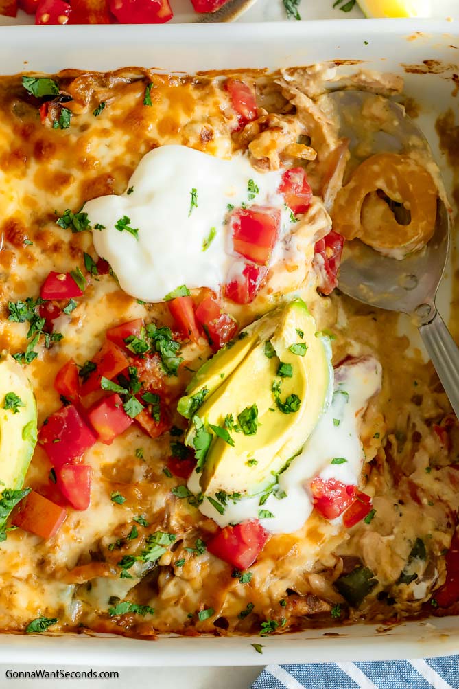 chicken breast fajita casserole topped with sliced avocados, sour cream and tomatoes 