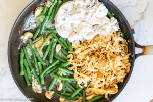 Step 8 how to make Paula Deen Green Bean Casserole, Add mushroom soup, onion rings, salt, pepper, and garlic powder.