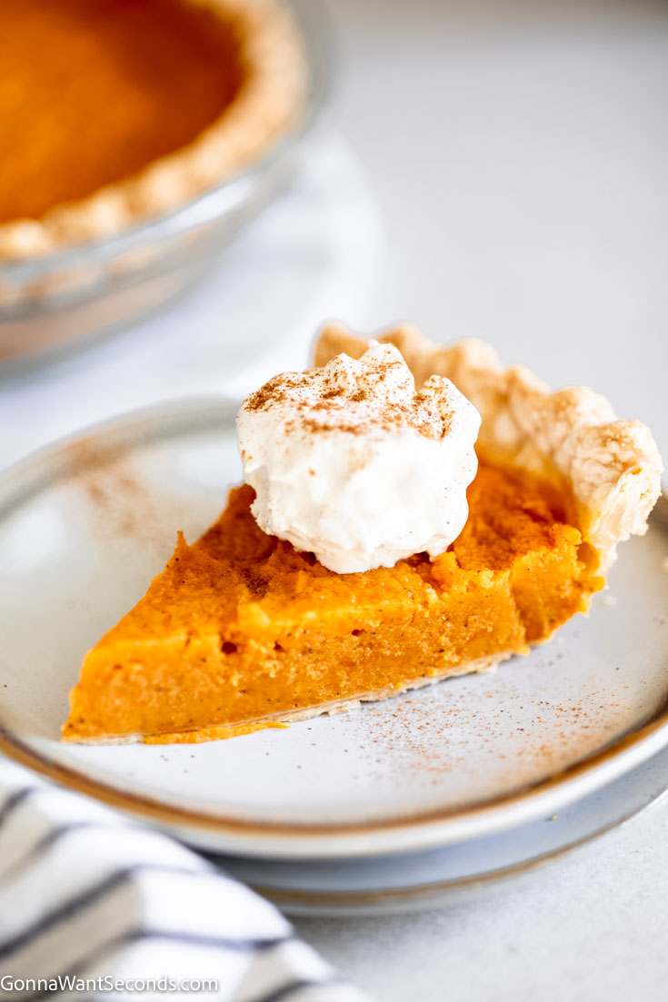 A slice of old fashioned sweet potato pie with whipped cream on top