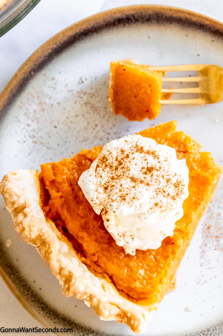 A slice of sweet potato pie with whipped cream on top