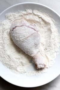 Step 2 how to make chicken & dumplings, Coat the chicken with the flour mixture and shake off excess.