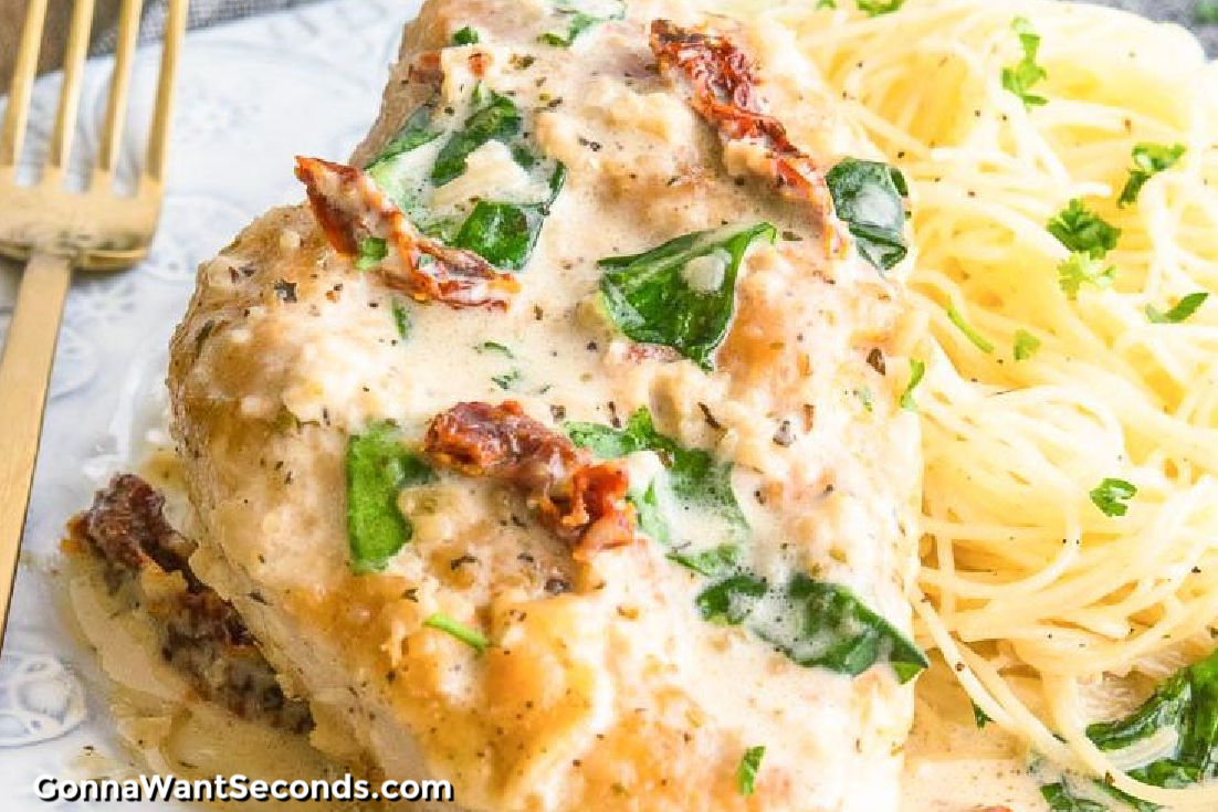 garlic tuscan chicken with pasta on the side, on a plate
