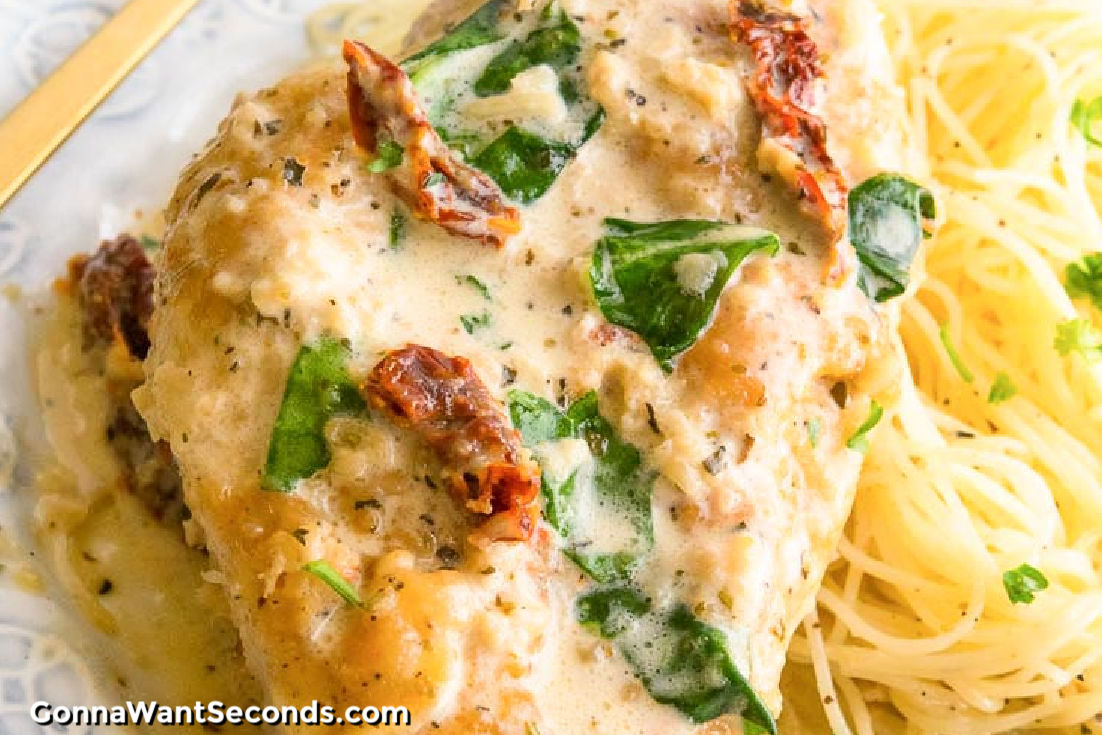creamy Tuscan garlic chicken with pasta on the side, on a plate