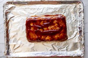Step 9 how to make chicken meatloaf, Pour half the glaze over the meatloaf. Brush the sauce over top and sides. Bake.