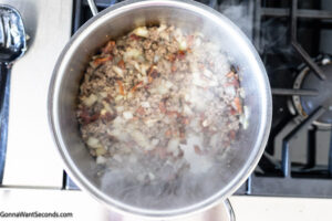 Step 3 how to make cowboy baked beans casserole, Saute the onion and add the garlic. Return the bacon and sausage to the pot.