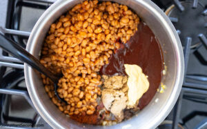 Step 4 how to make cowboy baked beans, Add canned beans, BBQ sauce, sugar, chili powder, diced chiles, Creole mustard, liquid smoke, hot sauce;