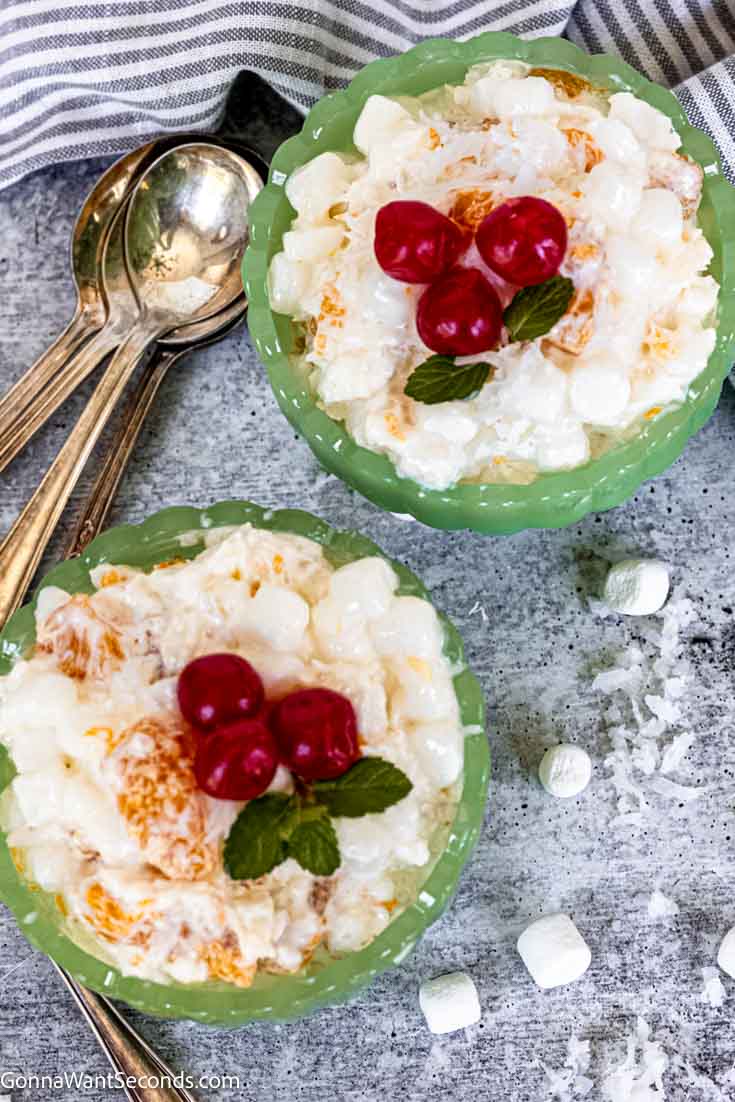 My mom often made this 5 cup salad for the family. It has tangy citrus, sweet mandarin oranges, fluffy marshmallow, shredded coconut, and sour cream. #5cupsalad #fivecupsalad 5 cup salad dessert with cherries on top in a green sherbet glass