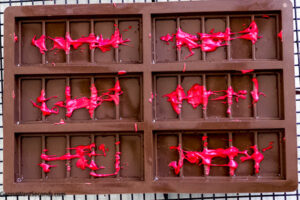 Step 1 how to make Dubai bar, Drizzle the colored chocolate into the chocolate mold.