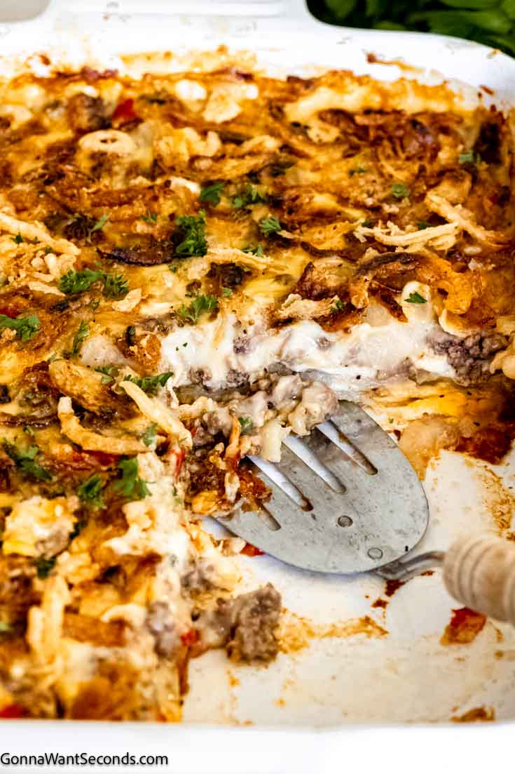 This comforting and hearty hobo casserole uses the layering of potatoes, cheese, spiced meat, and veggies, topped with a creamy savory gravy. #hobocasserole #beefpotatocasserole hobo casserole with ground beef a portion scooped out