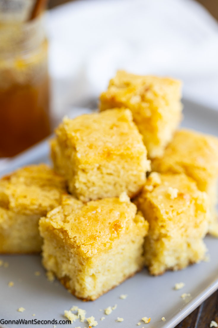 If you're a fan of sweet cornbread, our honey butter cornbread is the recipe you've been looking for! Sweet, tender and delicious! #cornbread #honeybuttercornbread a pile of sliced honey butter cornbread