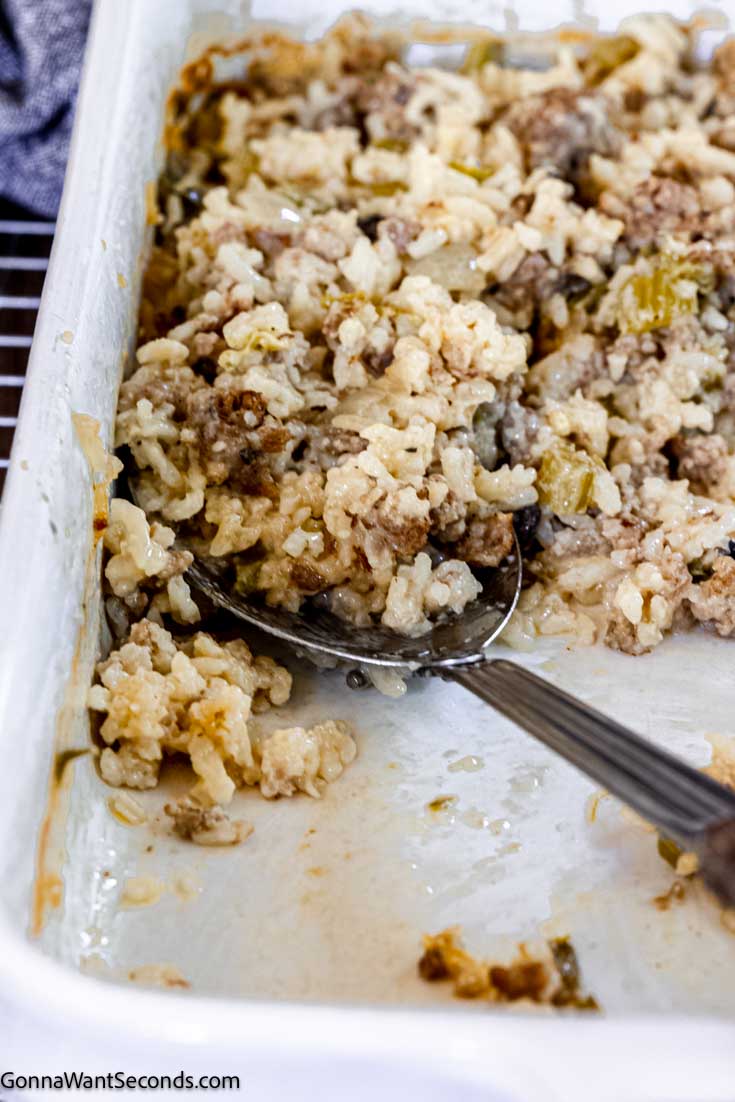 This quick and easy sausage and rice casserole has sausage, celery, onions, garlic, and rice all in a creamy chicken-based gravy. A perfect weeknight meal! #sausageandrice #sausageandricecasserole Scooping a portion of sausage and rice casserole