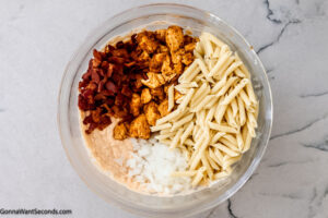 Step 4 how to make buffalo ranch chicken casserole, Add in the cooked chicken, cooked bacon, cooked pasta, and onion.
