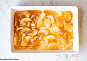 Step 1 how to make caramel apple dump cake, Pour both cans of apple pie filling into the baking dish.