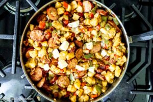 Step 4 how to make smothered potatoes and sausage, Add garlic. Pour in the chicken broth over the veggies and add butter. Cook until the potatoes are tender.